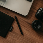 Photo editing decisions represented by a calm editorial workspace with a tablet, stylus, and camera, emphasising judgement and restraint rather than tools.