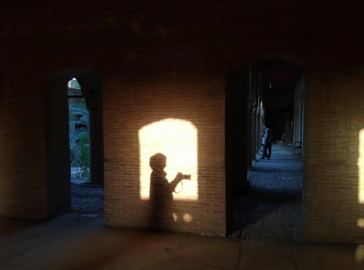 Photographer’s shadow framed by archways showing how photography composition decisions change the frame