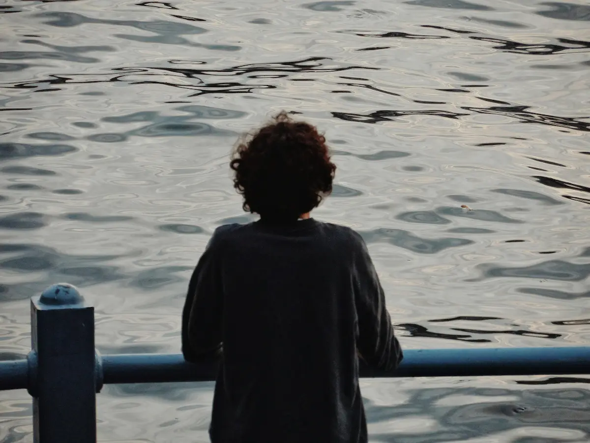 Photography observation practice shown as quiet attention, with a person looking over water in a calm, unforced moment.